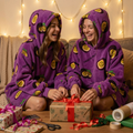 Two friends laughing while wrapping Christmas presents in matching Passion Fruit Snugzillas